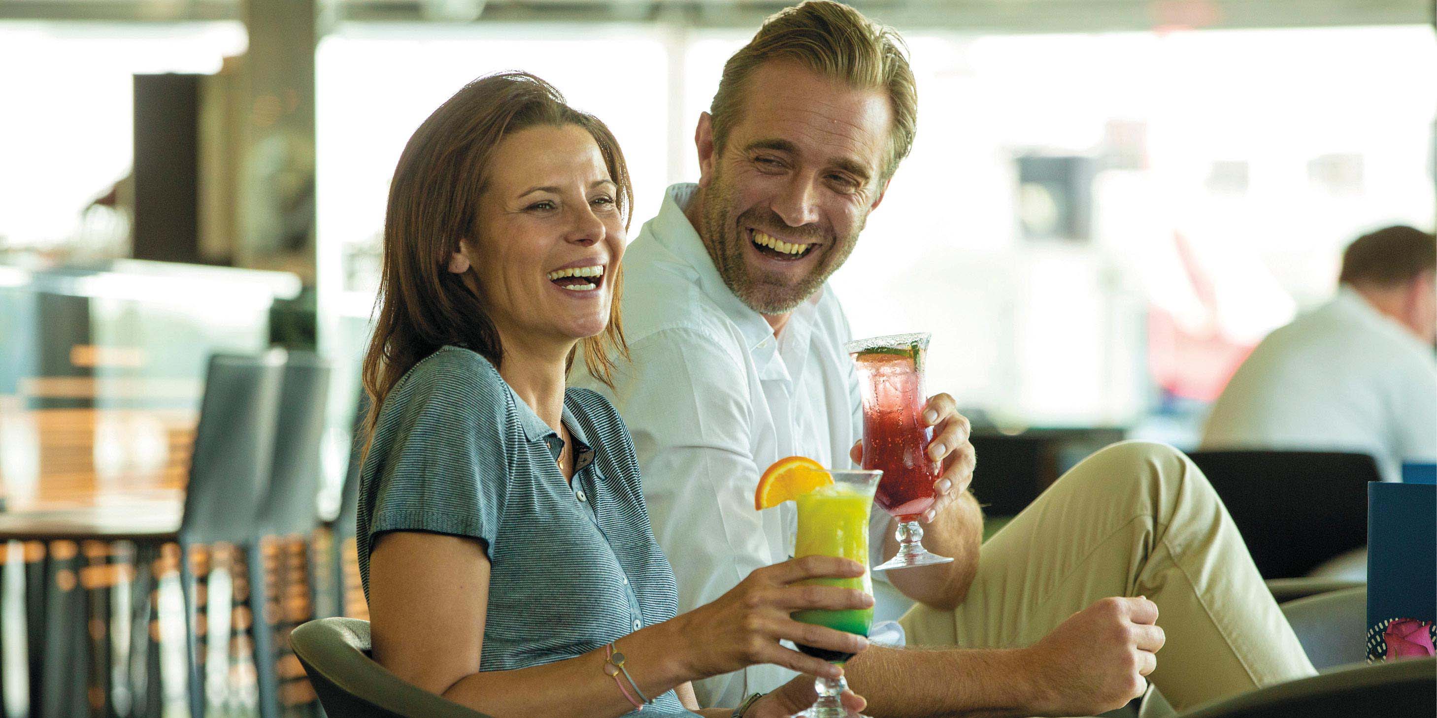 Man and woman laughing as they enjoy their cocktails in the surrounds of a modern bar and lounge space