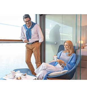 A man and woman having a beverage in the Scenic Sun Lounge area of a Royal Owners Suite.