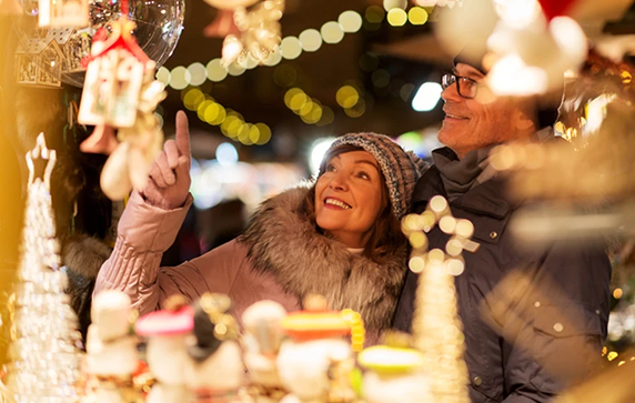 A couple looking at the festive decorations at the stalls in a European Christmas market.