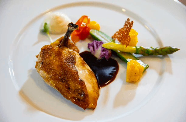 A close-up of a chicken breast and colourful vegetables on a plate  