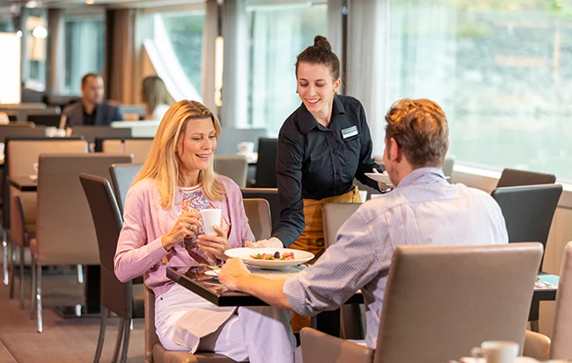 A man and woman being served plates of food at Crystal Dining on board a Scenic cruise ship in Budapest, Hungary.