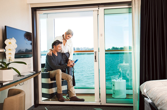 A couple enjoying the Scenic Sun Lounge in their Junior Balcony Suite