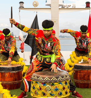 Traditional Asian drummers in vibrant costumes performing a cultural drum show on board Scenic Spirit