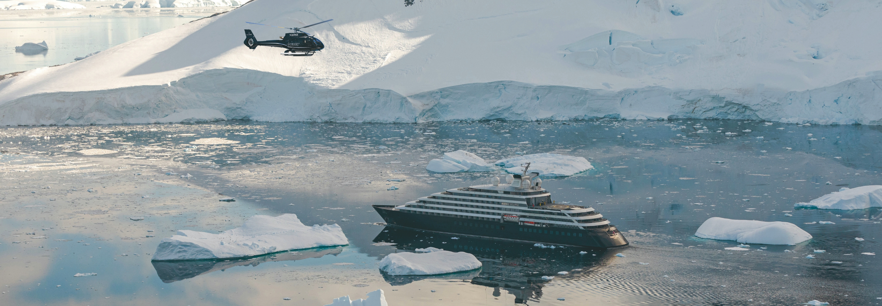 Scenic Eclipse cruise ship in polar setting with helicopter flying above