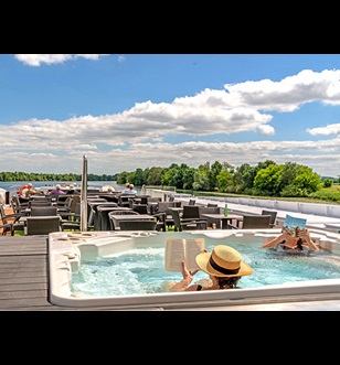 Two guests relax reading books in the vitality pool on the Sun Deck as other guests sit in the background