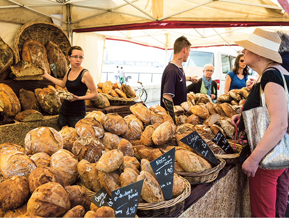 Women buying a loaf of bread at a local market in Bordeaux
